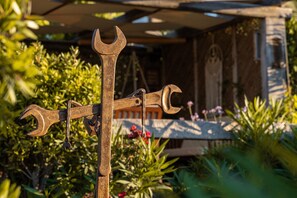 Een tuin met een metalen sculptuur van een sleutel en een houten bankje.