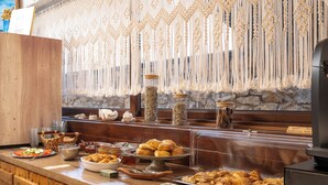 Un mostrador de buffet con diferentes opciones de comida y una cortina decorativa de macramé.