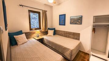 Un dormitorio con dos camas, una ventana con cortinas, un ventilador de techo y una obra de arte en la pared.