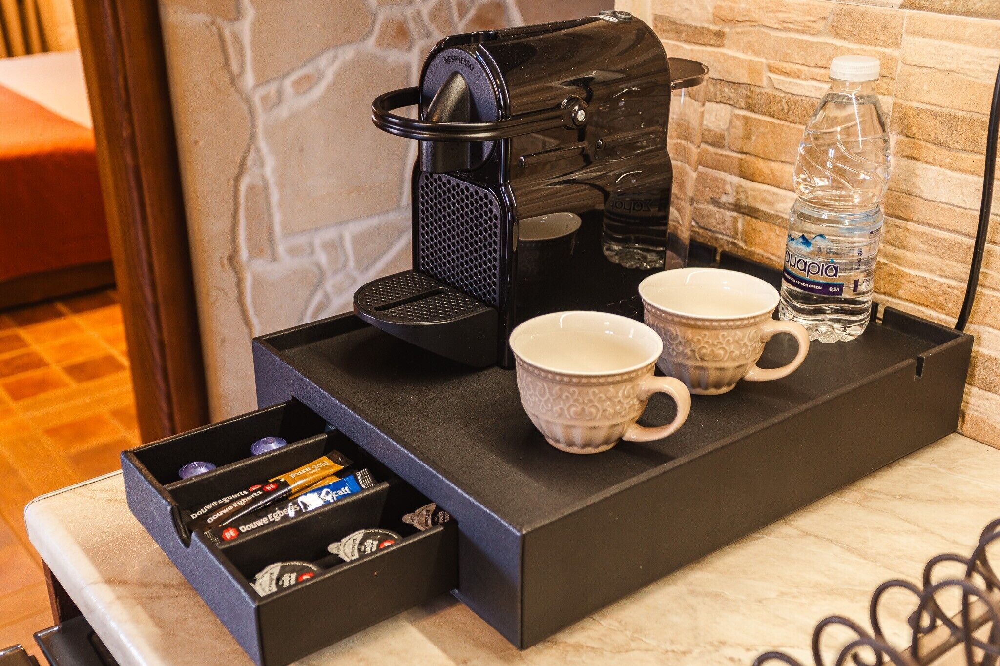 A coffee machine with a water bottle and two cups on a tray.