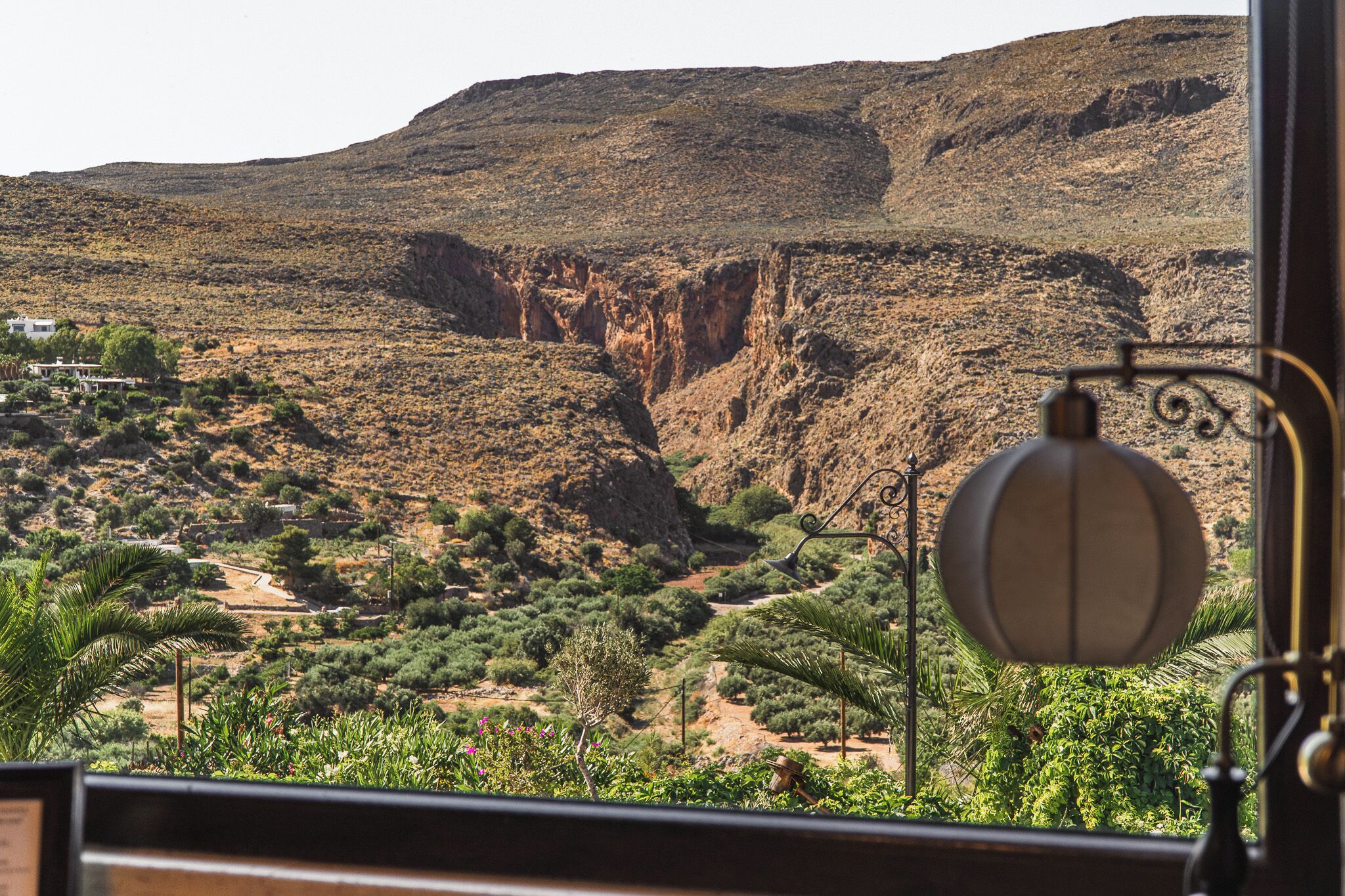 Vista de un paisaje desértico con una montaña al fondo, una carretera y algo de vegetación.