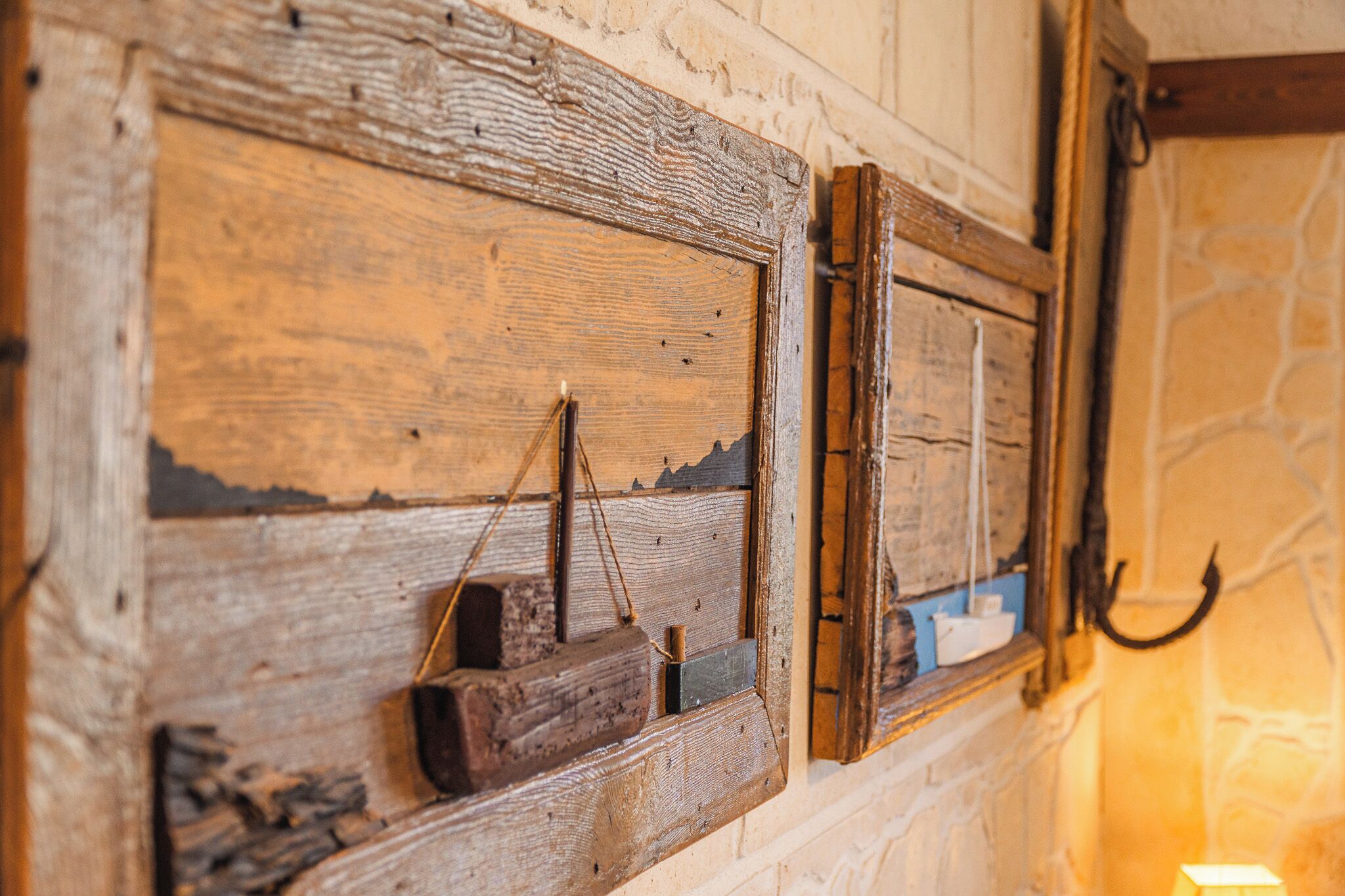 A rustic wooden wall with a small wooden shelf holding a candle and a hook.
