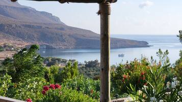 A wooden pergola with a view of a coastal landscape, including a body of water and distant mountains.