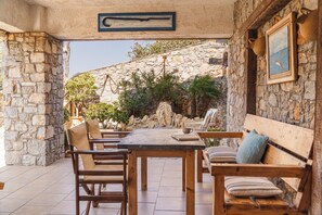 Un patio al aire libre con paredes de piedra, una mesa de madera y sillas.