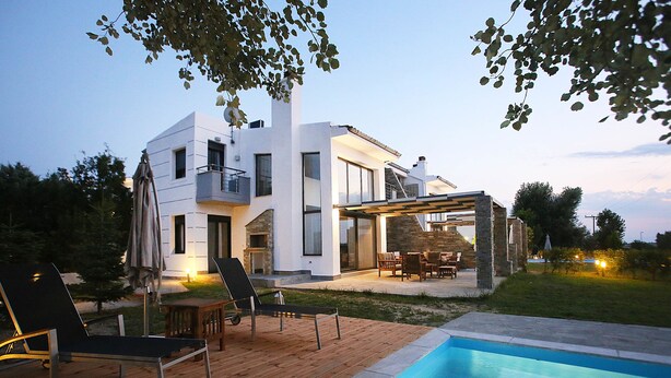 Een modern huis met een zwembad, buitenmeubels en een patio.