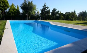 A rectangular swimming pool with clear blue water, surrounded by a concrete deck and a grassy area with trees. - Sunny Sani Luxury Villas (Kassandra)