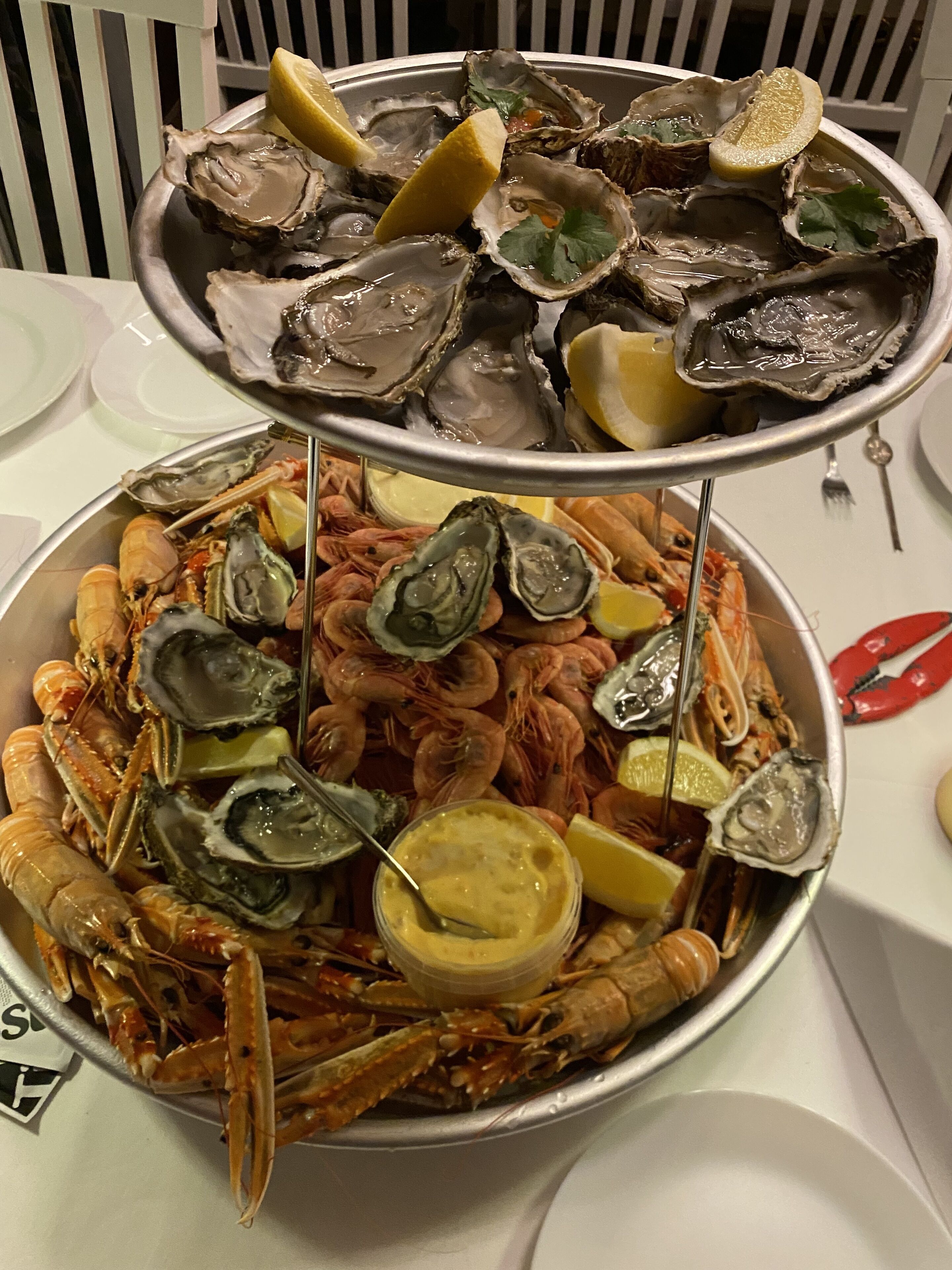 A seafood platter with oysters and shrimp, served on a metal tray.