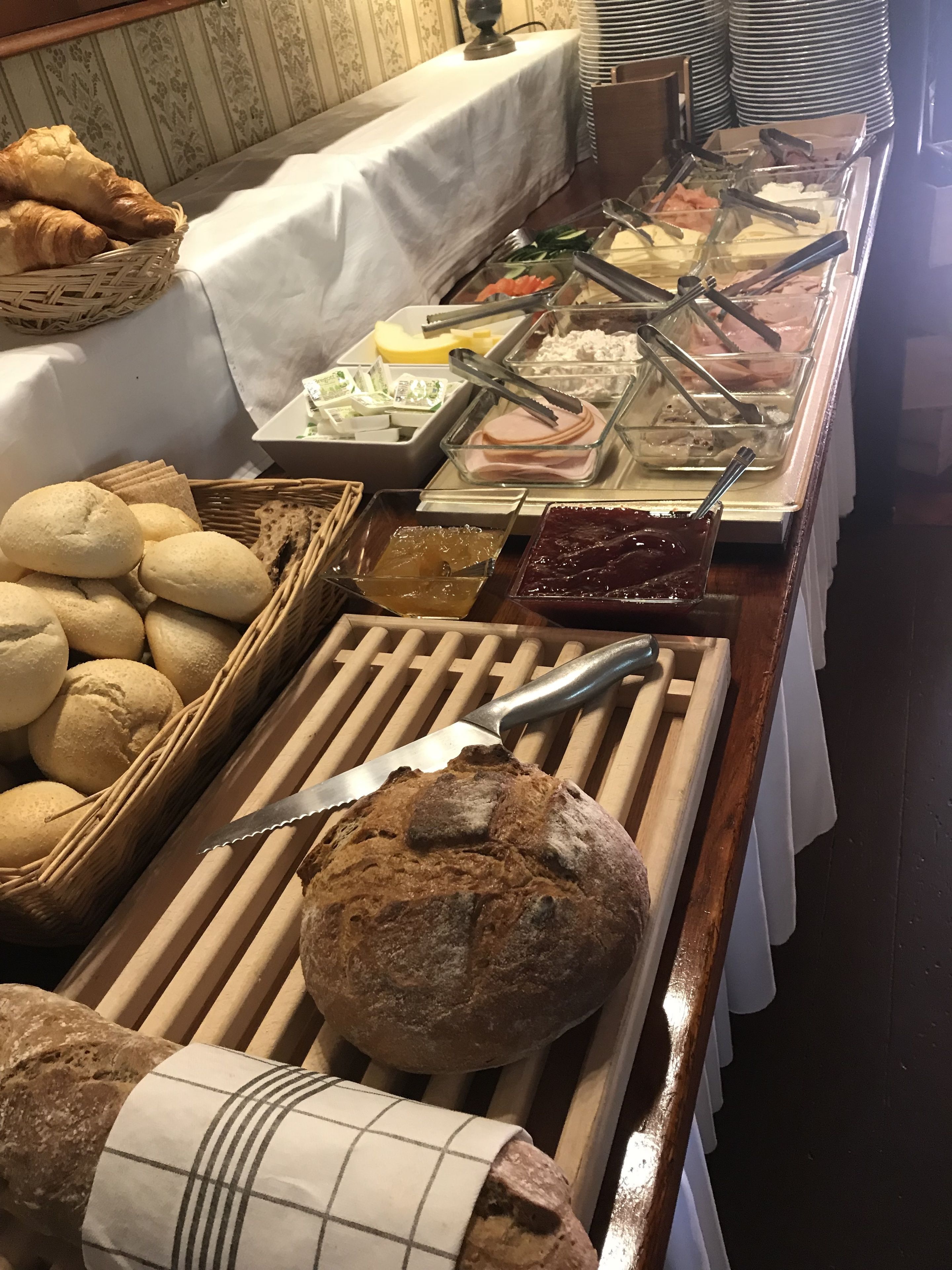 Ein Buffet mit verschiedenen Speisen, darunter Brot, Gebäck und einer Auswahl an Aufstrichen.