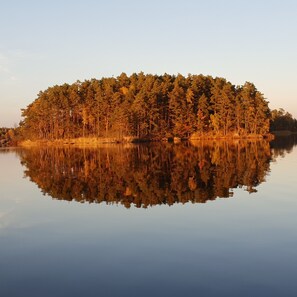 A tranquil lake with a forested island reflecting in the water. - Wärdshuset Furuliden (Vittsjo)