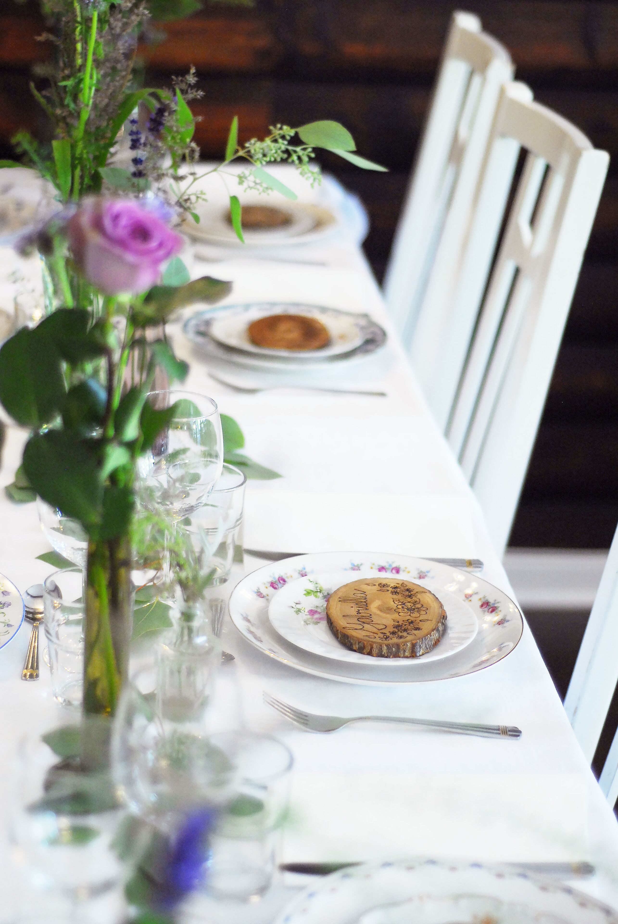 A dining table set with plates, glasses, and a cake.