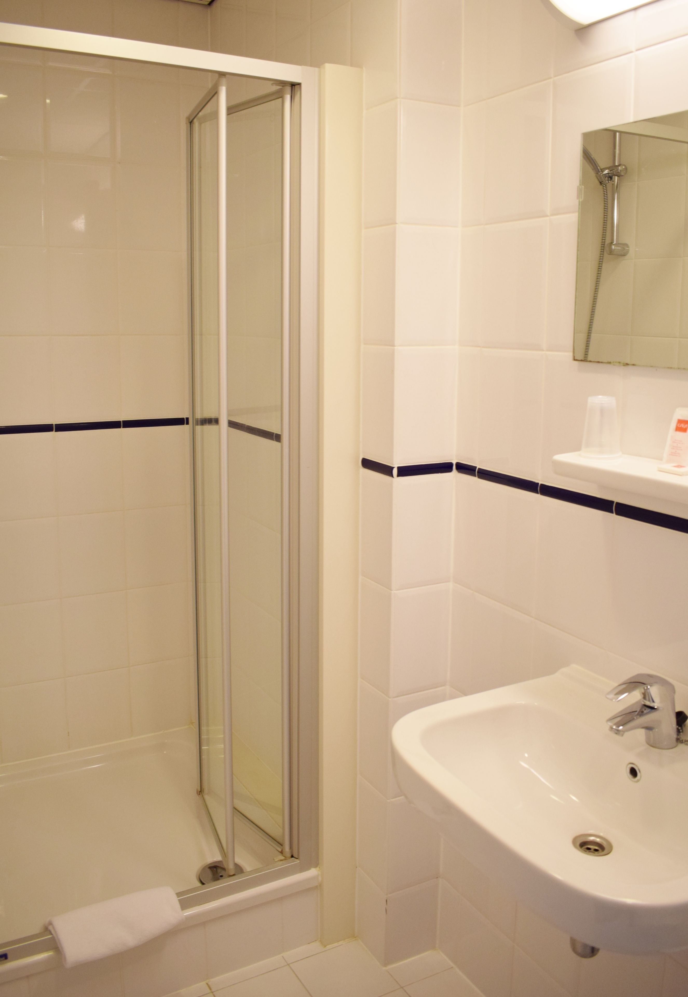 Une salle de bain avec une douche à parois de verre, un lavabo blanc et un miroir au-dessus.