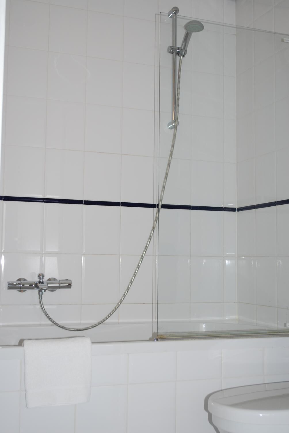 A bathroom with a glass-enclosed shower, a white bathtub, and a towel rack.
