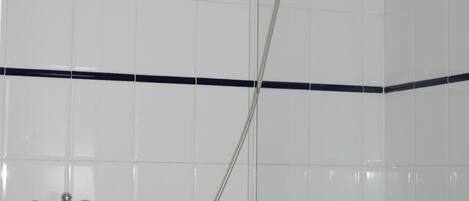 Un baño con ducha de vidrio, bañera blanca y un perchero para toallas.