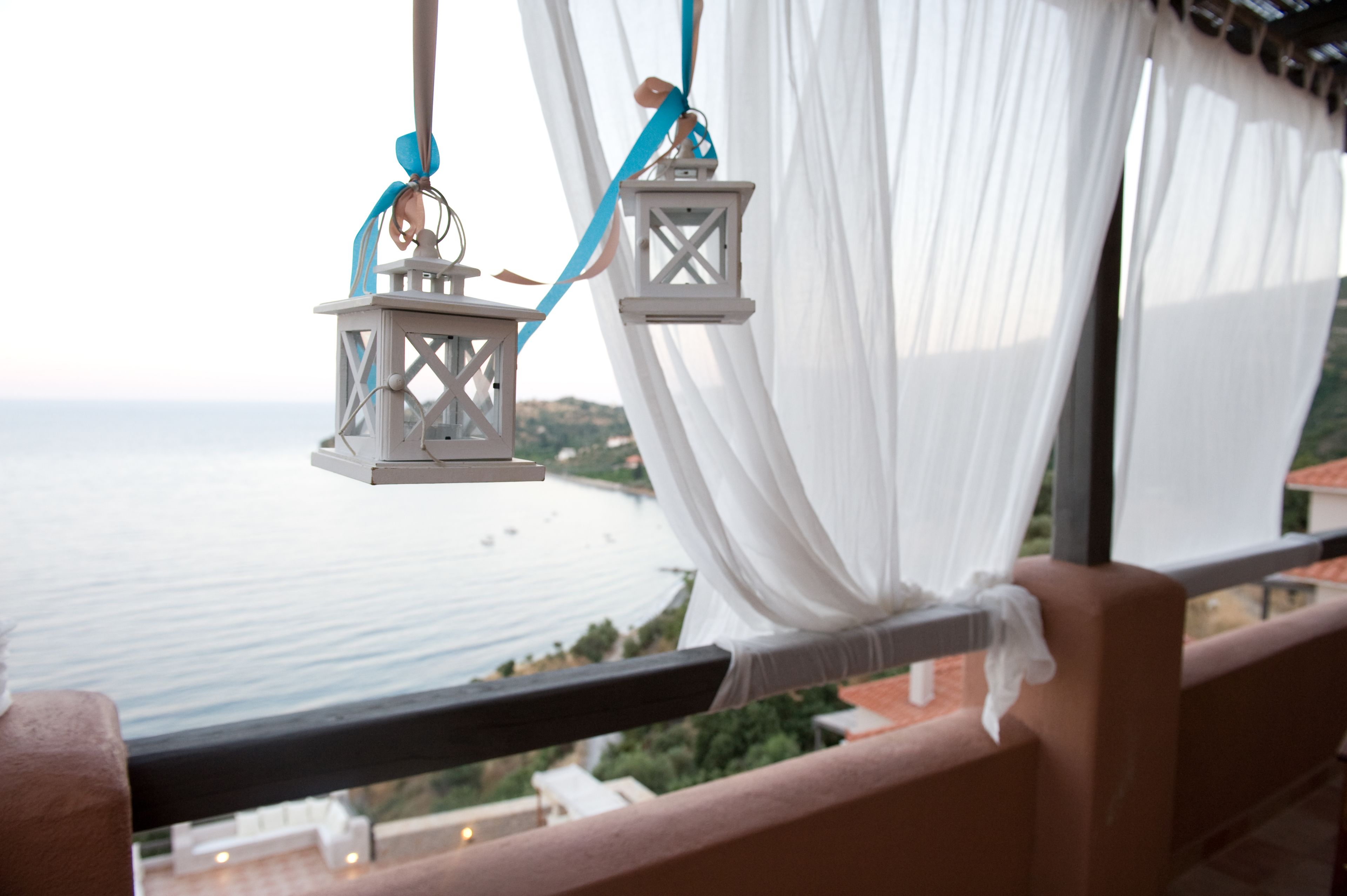 Un balcon agrémenté de rideaux blancs et de deux lanternes suspendues.