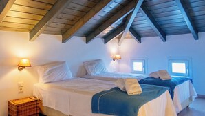 Ein Schlafzimmer mit zwei Betten, Holzbalken und zwei Wandleuchten.