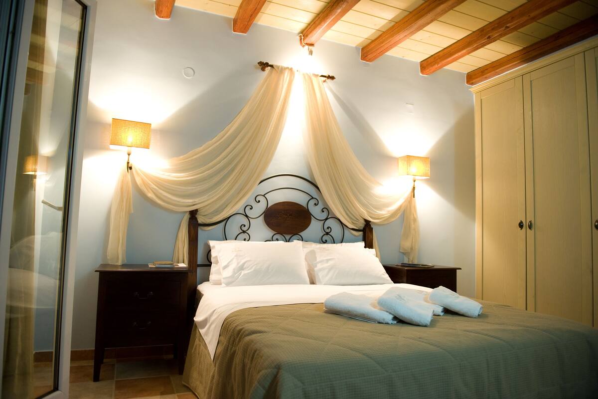 Une chambre à coucher comprenant un lit, deux tables de chevet, une commode, une armoire et une fenêtre avec des rideaux.
