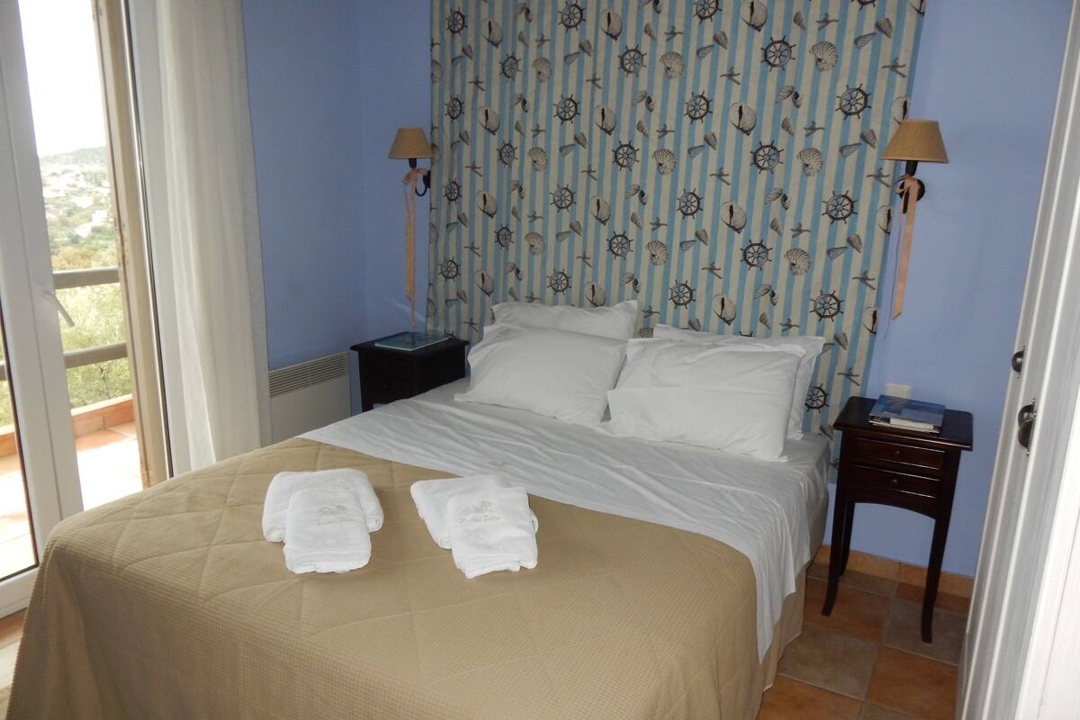 Un lit bien fait, avec du linge de lit blanc et deux serviettes posées au pied du lit.
