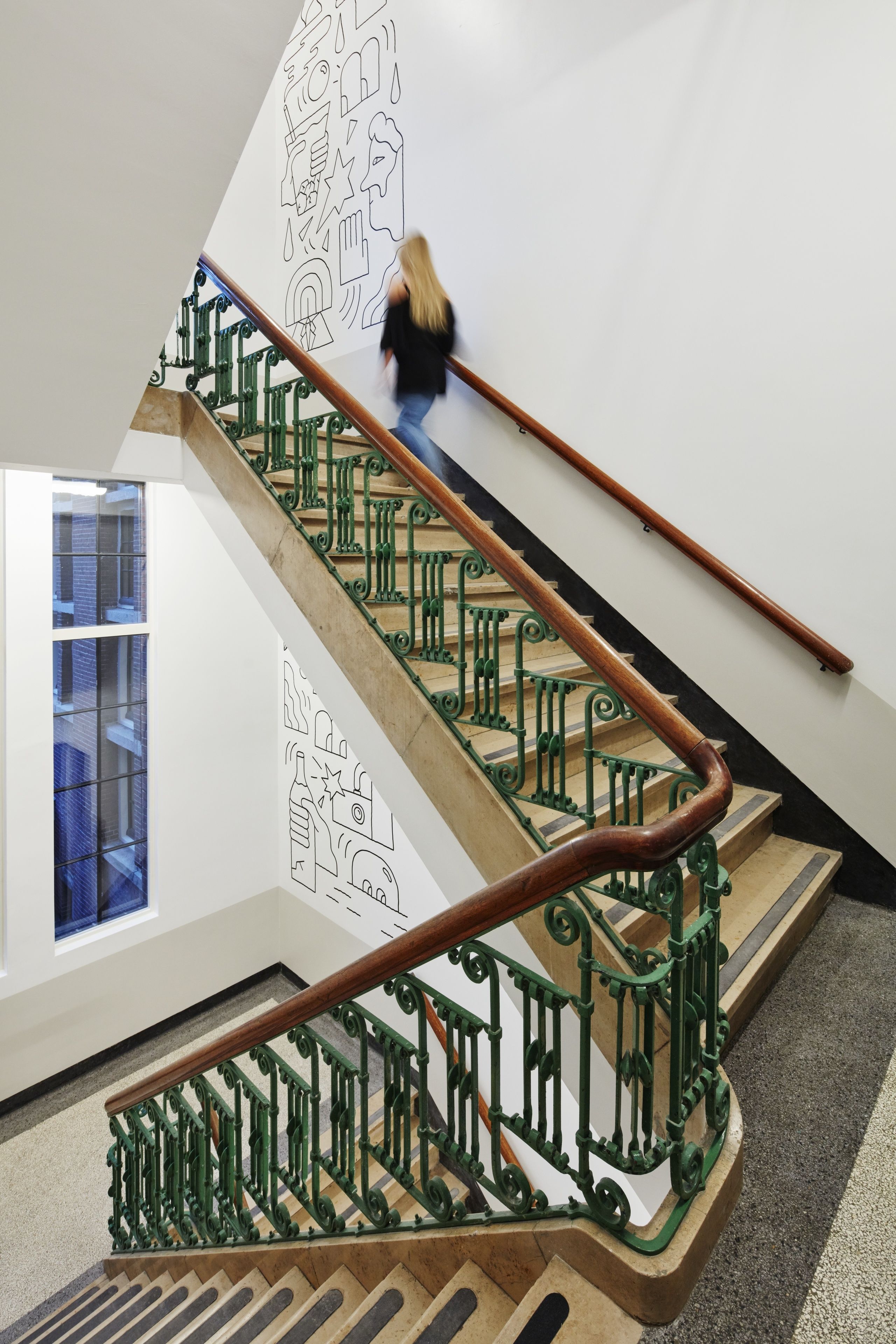 Una escalera con barandillas de metal verde y pasamanos de madera.