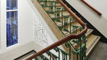 Una escalera con barandillas de metal verde y pasamanos de madera.
