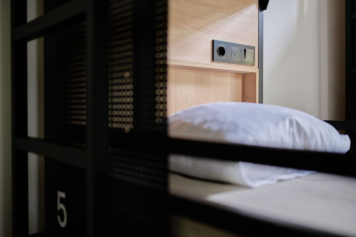 Un lit superposé avec un oreiller blanc et une tête de lit en bois.