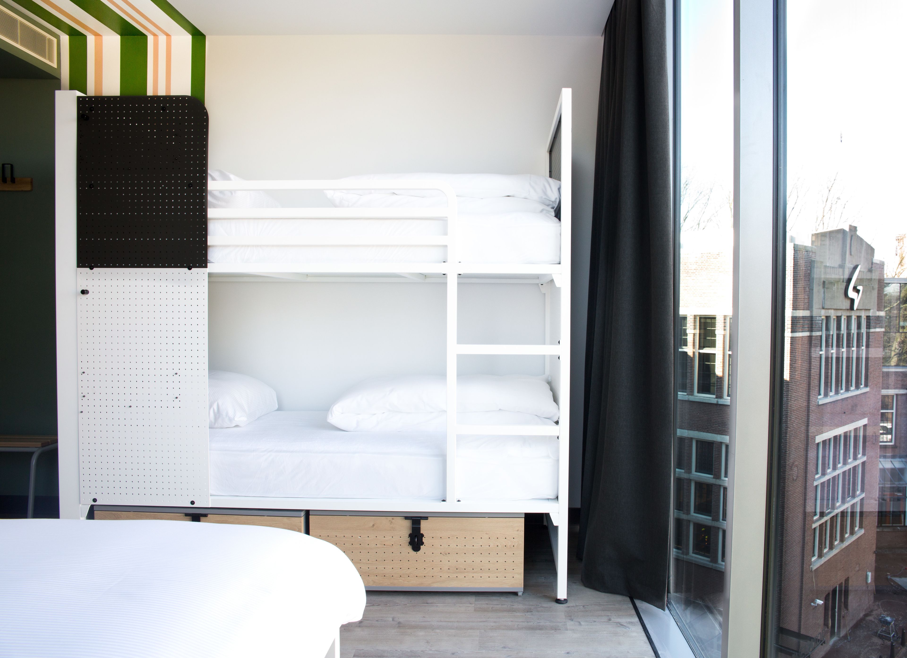 Een slaapkamer met stapelbed en uitzicht op gebouwen.
