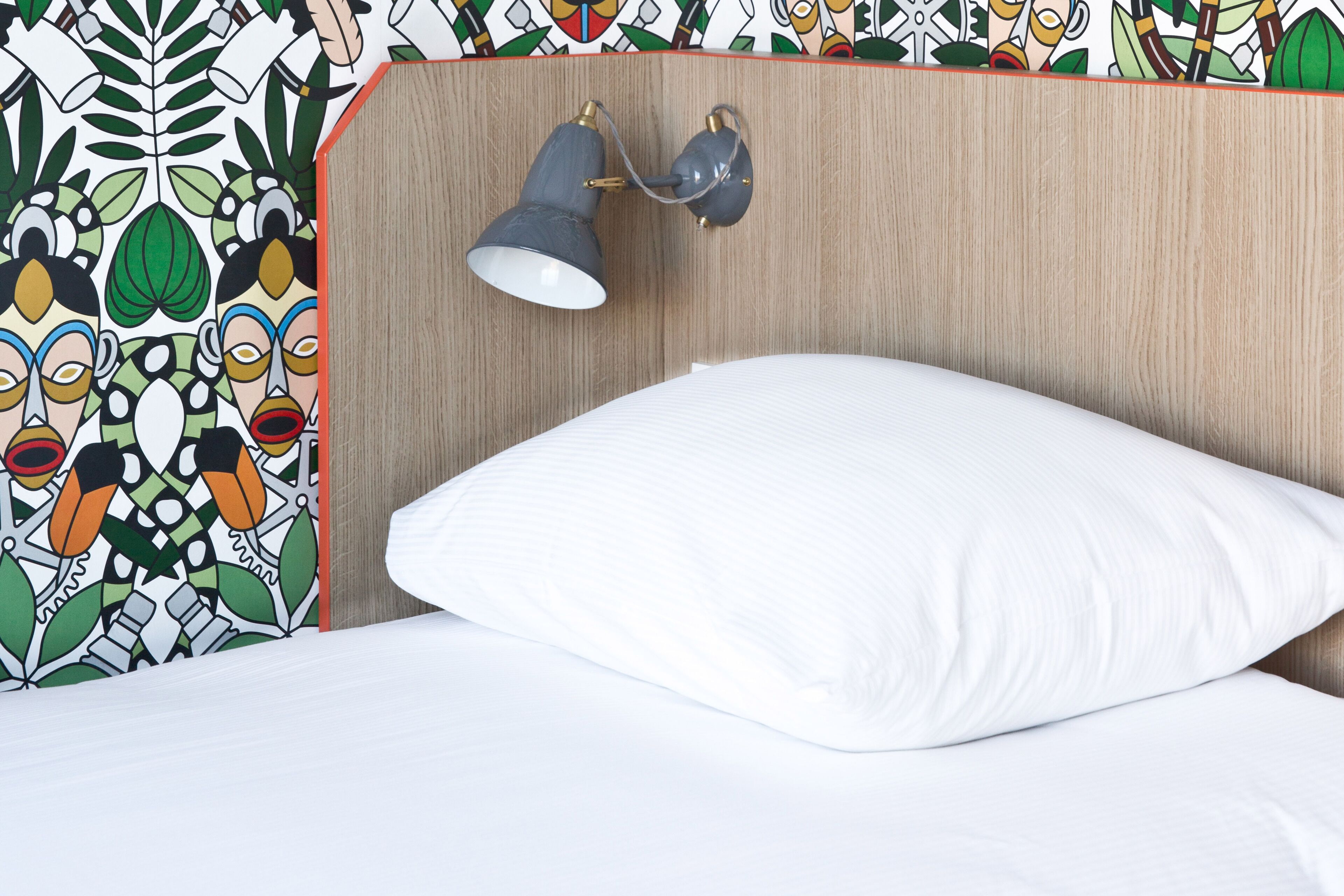 Een bed met een wit kussen en een hoofdbord met houten afwerking.