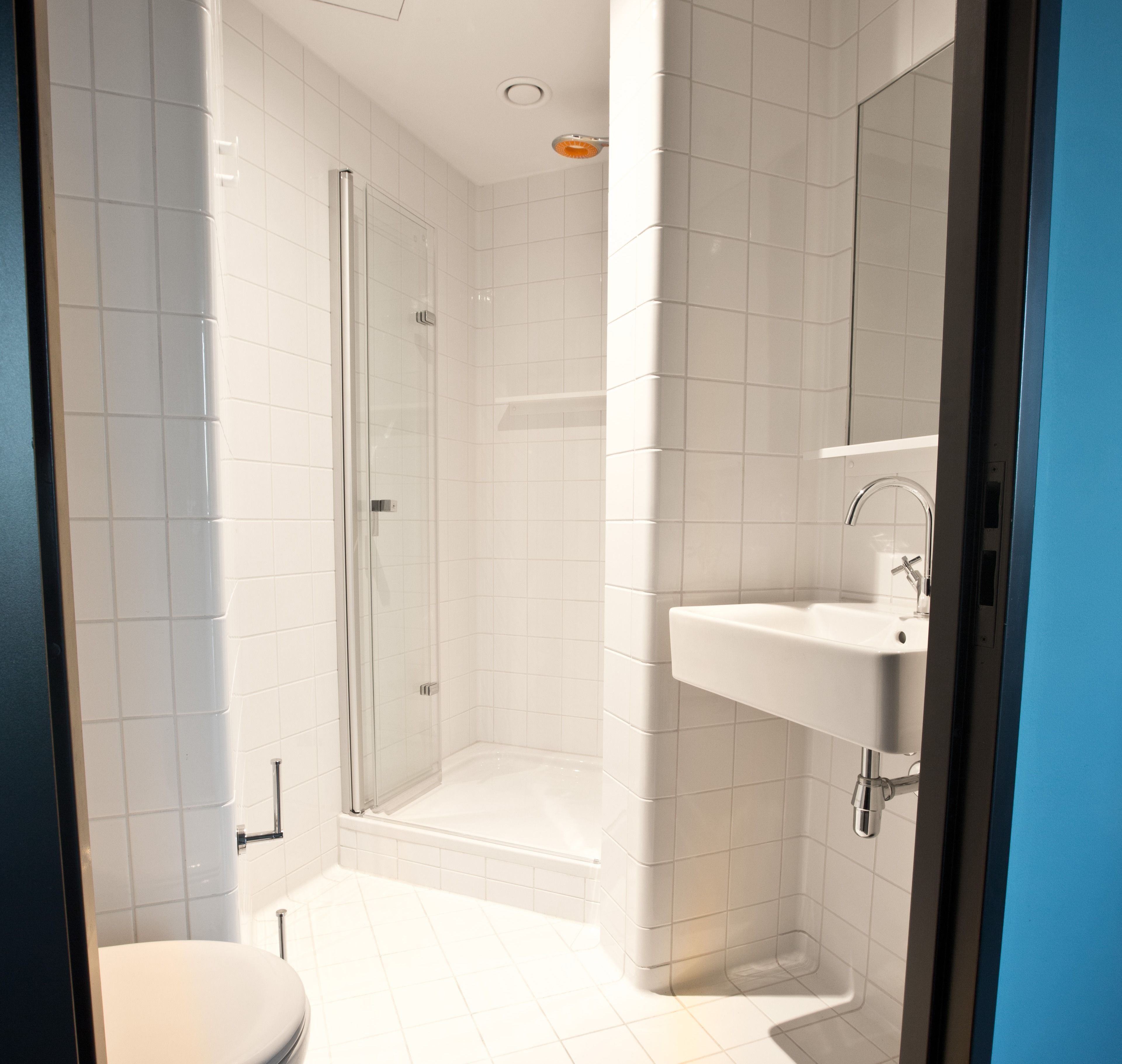 A modern bathroom with a glass shower enclosure, a white sink, and a toilet.