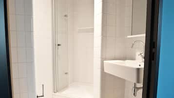 A modern bathroom with a glass shower enclosure, a white sink, and a toilet.