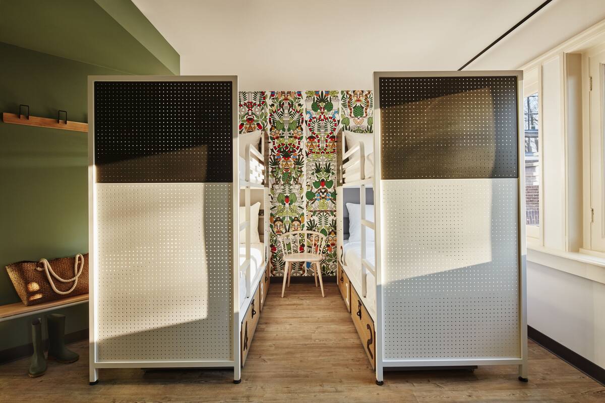 Une pièce avec des lits superposés, un banc en bois et un papier peint à motifs.