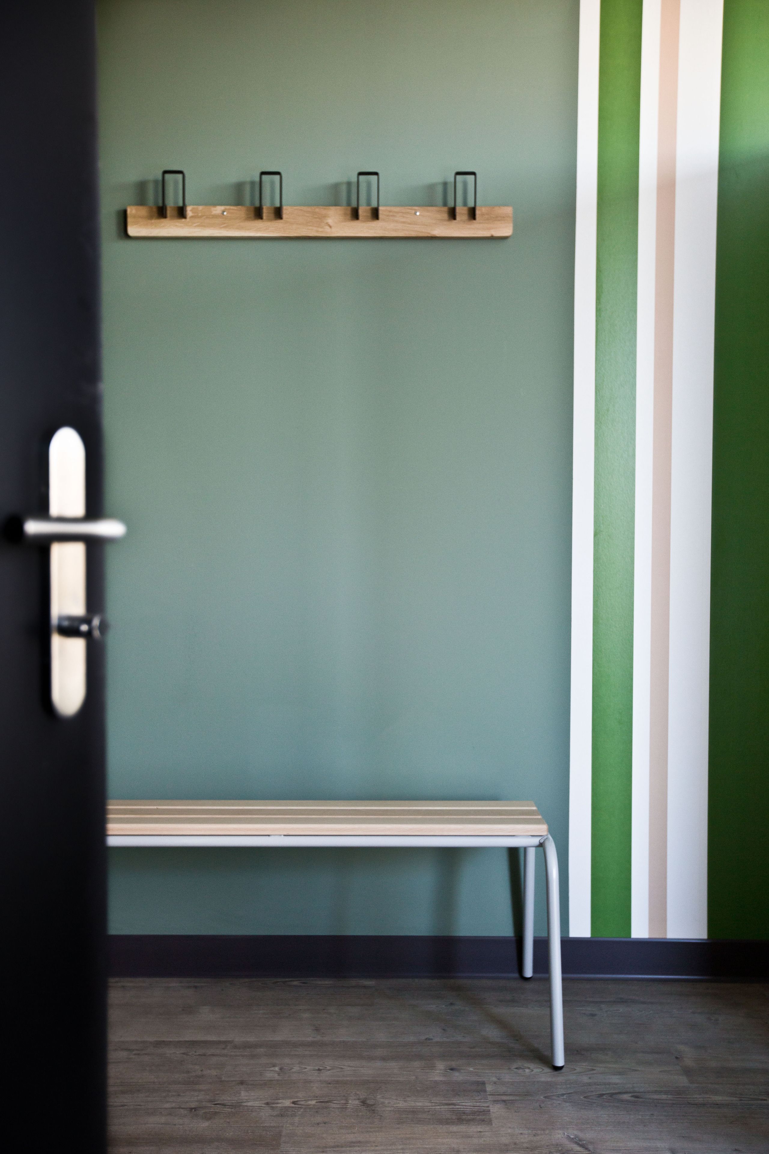 A bench in a hallway with a wooden shelf above it.