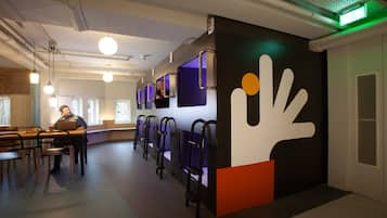 A modern interior with seating areas, a large wall art piece, and a person working at a desk.