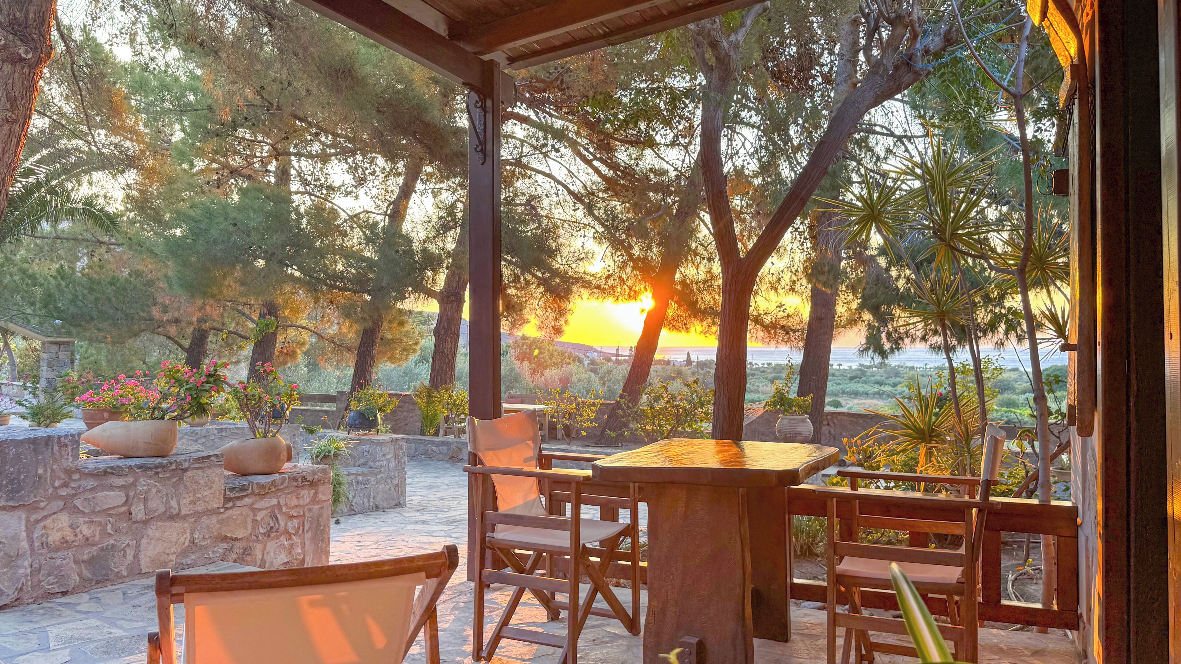 Un espacio de estar al aire libre cubierto con paredes de piedra, muebles de madera y plantas en macetas.