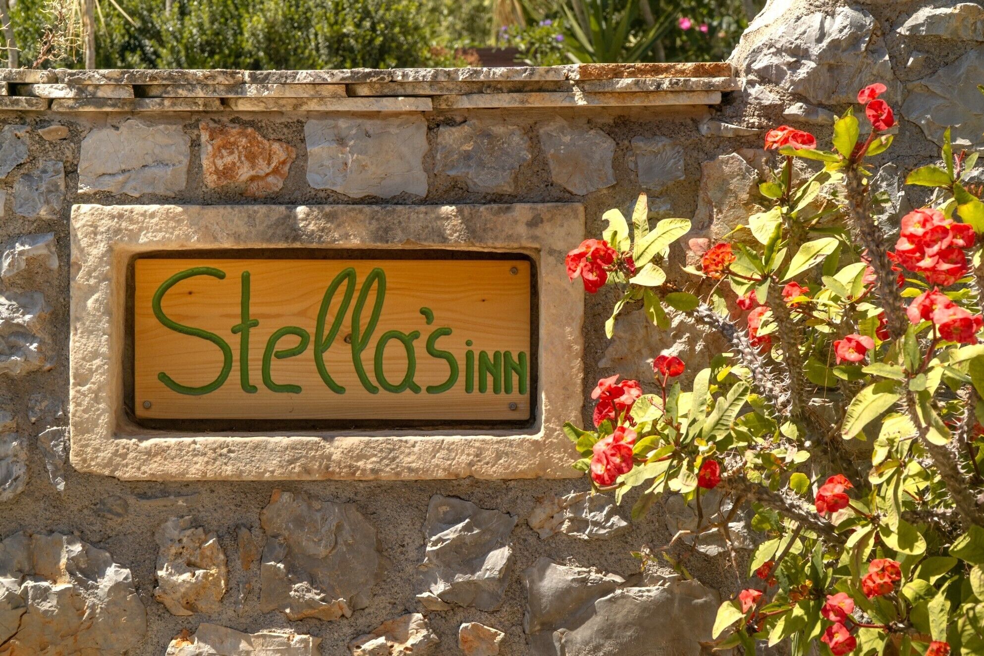 Un muro de piedra con un letrero de madera que dice 'Stella's Inn'.