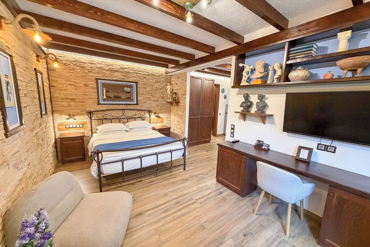 A bedroom with a bed, bedside tables, a desk, a chair, a TV, and a wardrobe.