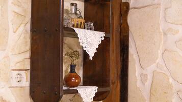 A wooden shelf with a vase and a pitcher, set against a stone wall.
