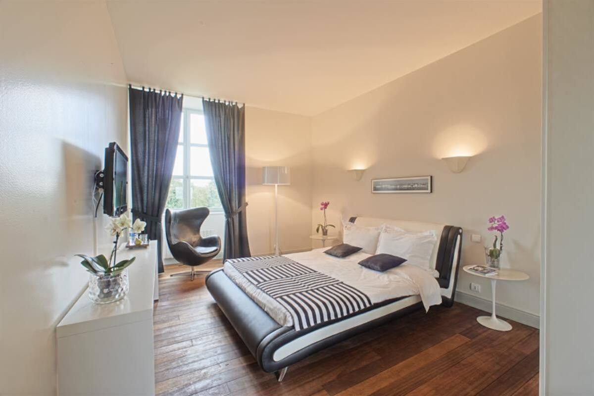 A modern hotel room with a bed, a chair, a small table, and a TV.