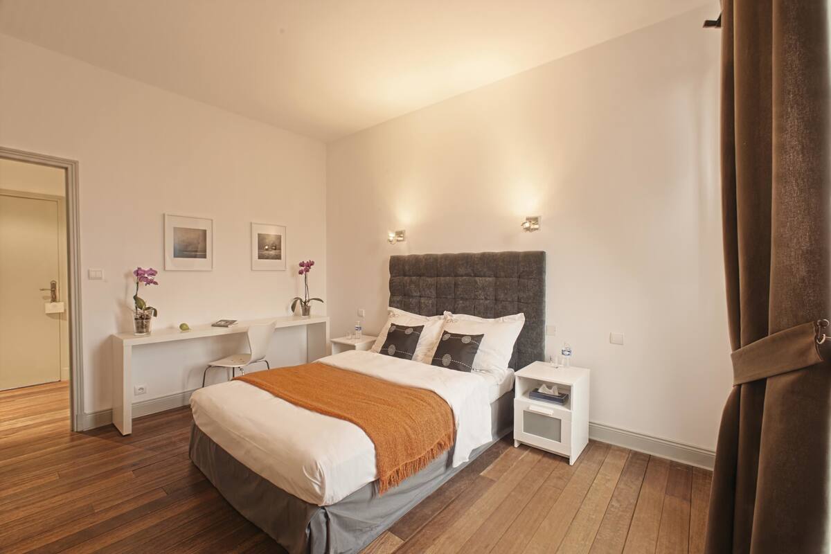 A bedroom with a bed, bedside tables, a desk, and a chair.