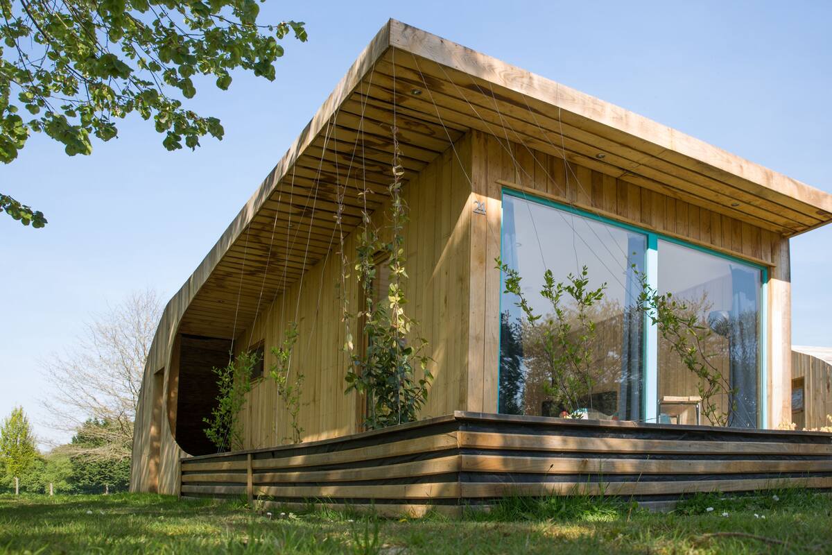 A modern wooden house with a sloped roof and large glass windows.