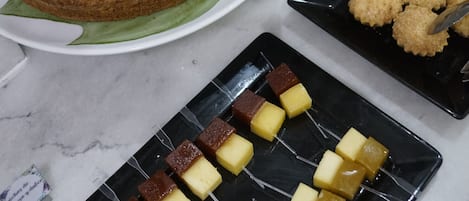 Una mesa de bufé con diversos postres, incluyendo un pastel, fruta y otras delicias dulces.