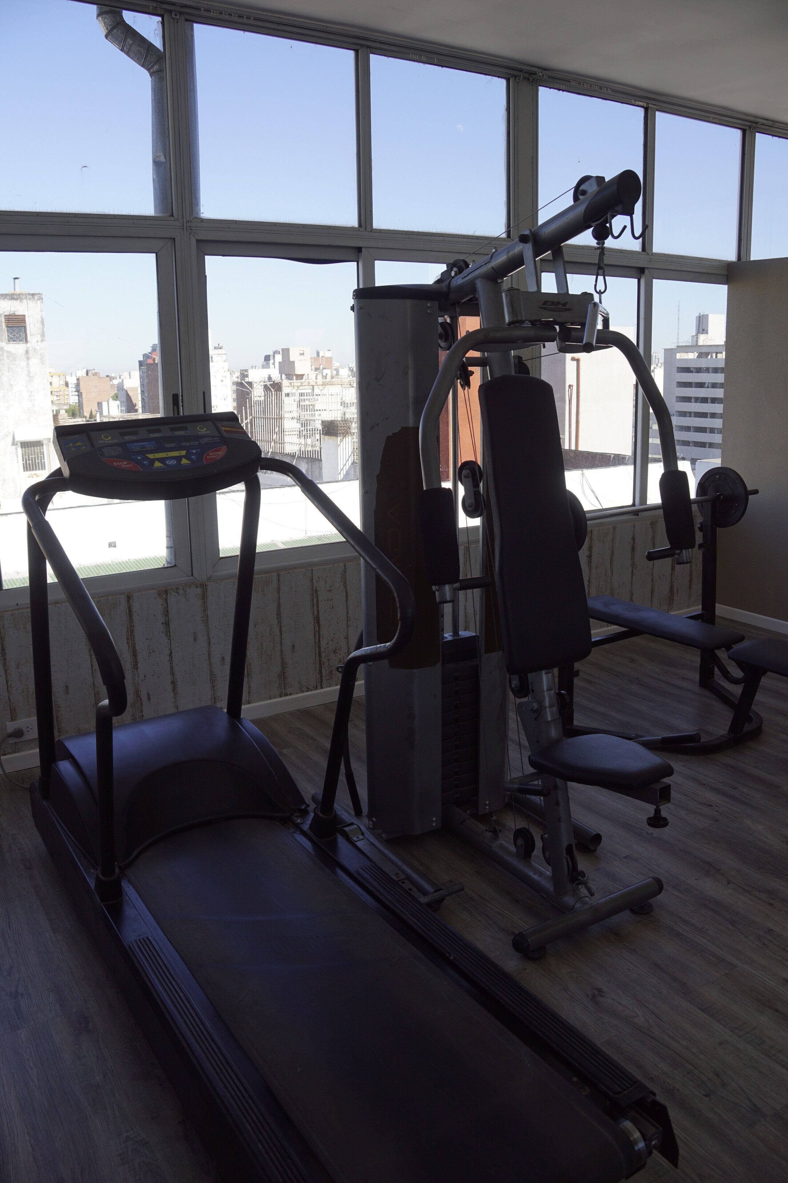 A gym with a treadmill, weight machines, and a bench.