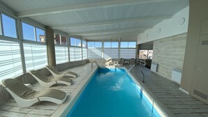 An indoor swimming pool with lounge chairs and a view of the city. - Howard Johnson by Wyndham Rosario (Rosario)