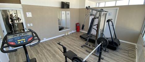 A gym with cardio equipment, weightlifting stations, and a mirror.