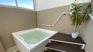 A bathroom with a bathtub, wooden steps, a potted plant, and a window. - Howard Johnson by Wyndham Rosario (Rosario)