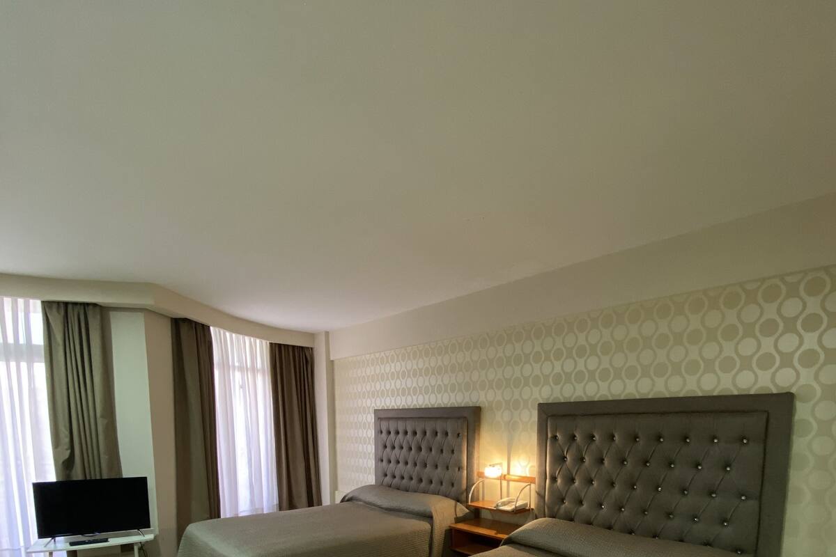 A hotel room with two beds, a TV, and a nightstand with a lamp.