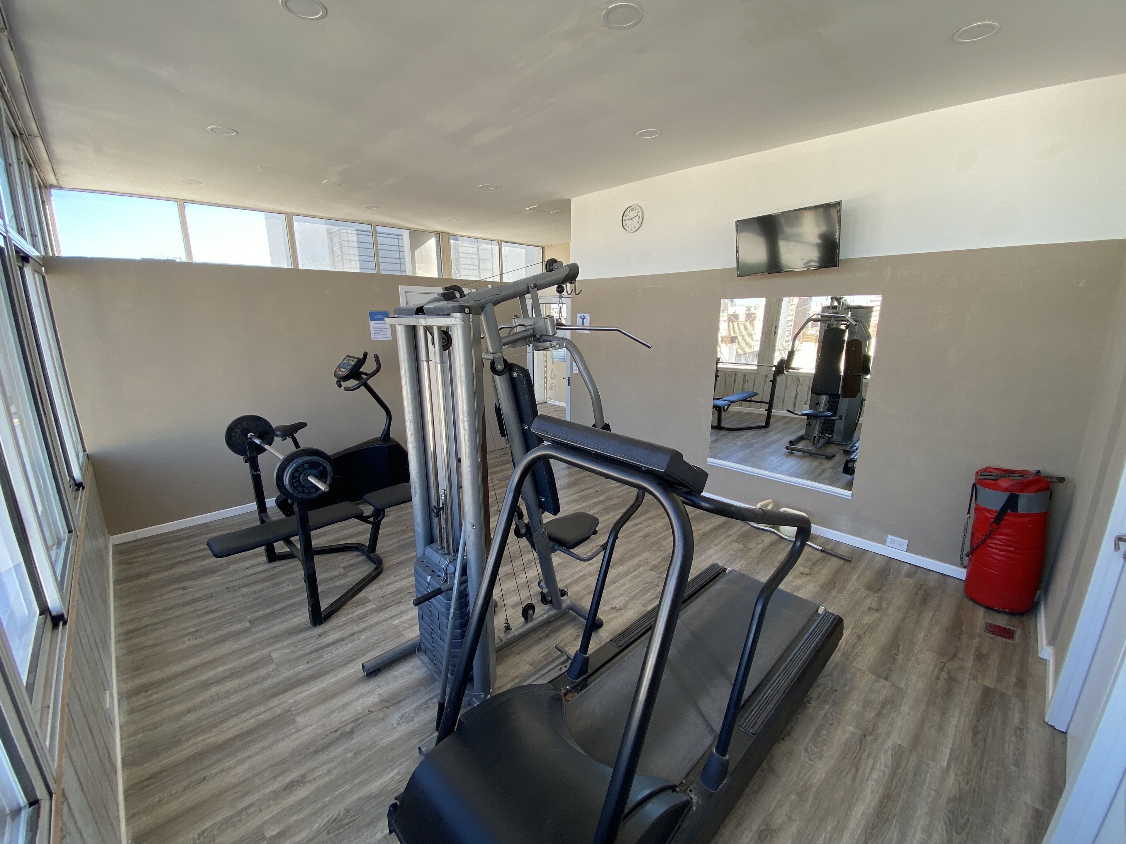 Uma academia com aparelhos de cardio, equipamentos de musculação e espelhos.