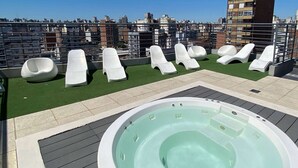 A rooftop terrace with a hot tub, lounge chairs, and a view of the cityscape. - Howard Johnson by Wyndham Rosario (Rosario)