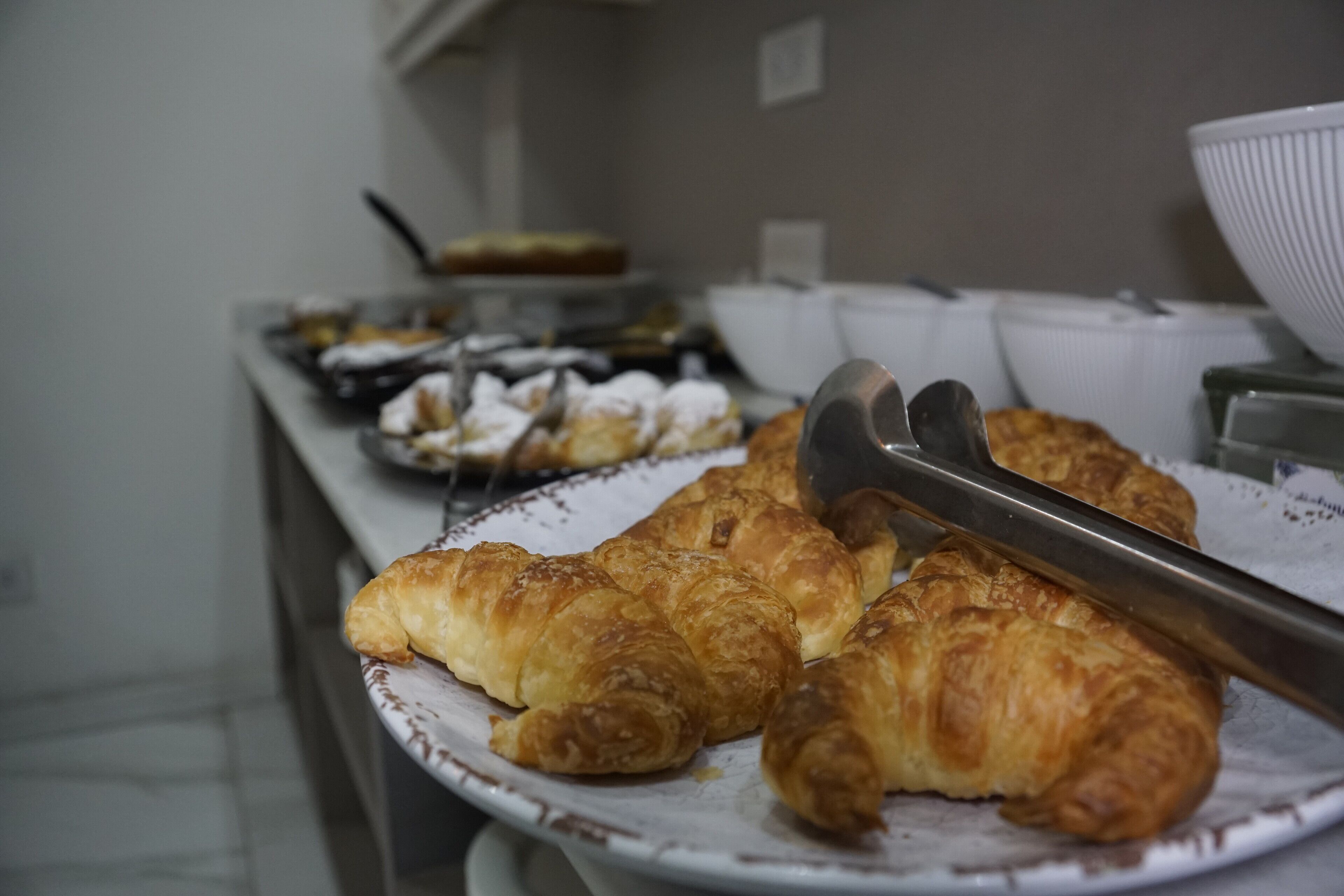 Una mesa de buffet con diversas pastas, incluyendo cruasanes, dispuestas en platos.