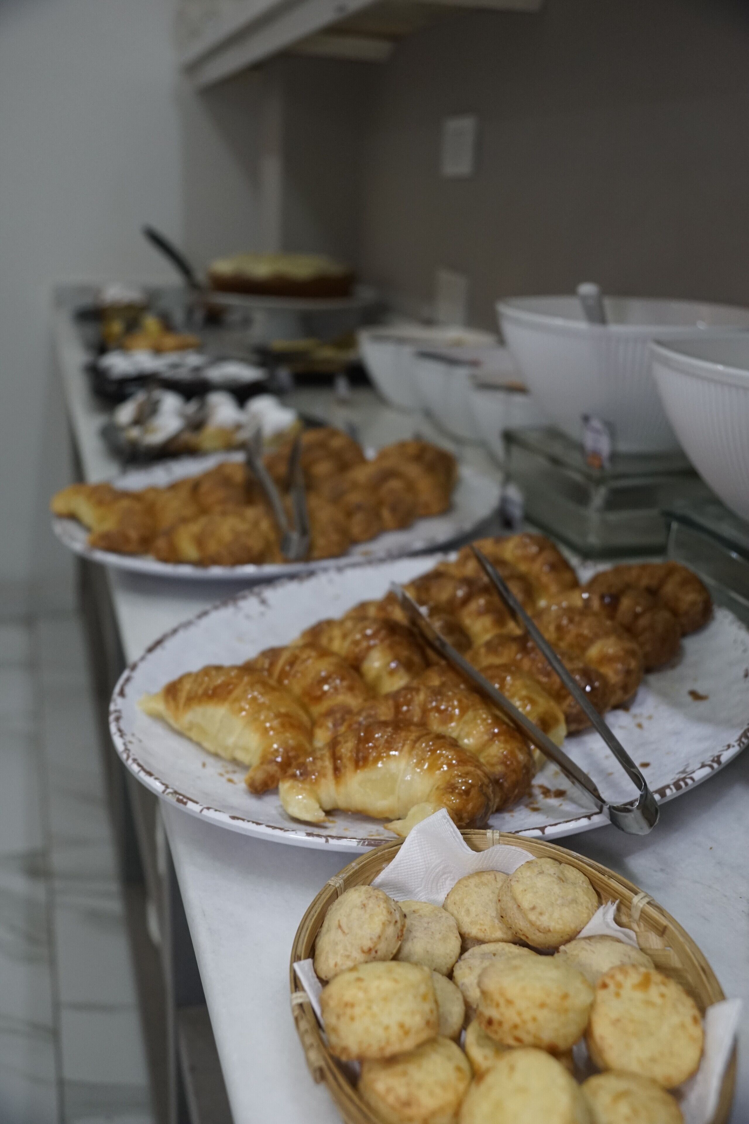 A buffet table with various food items including pastries and bread.