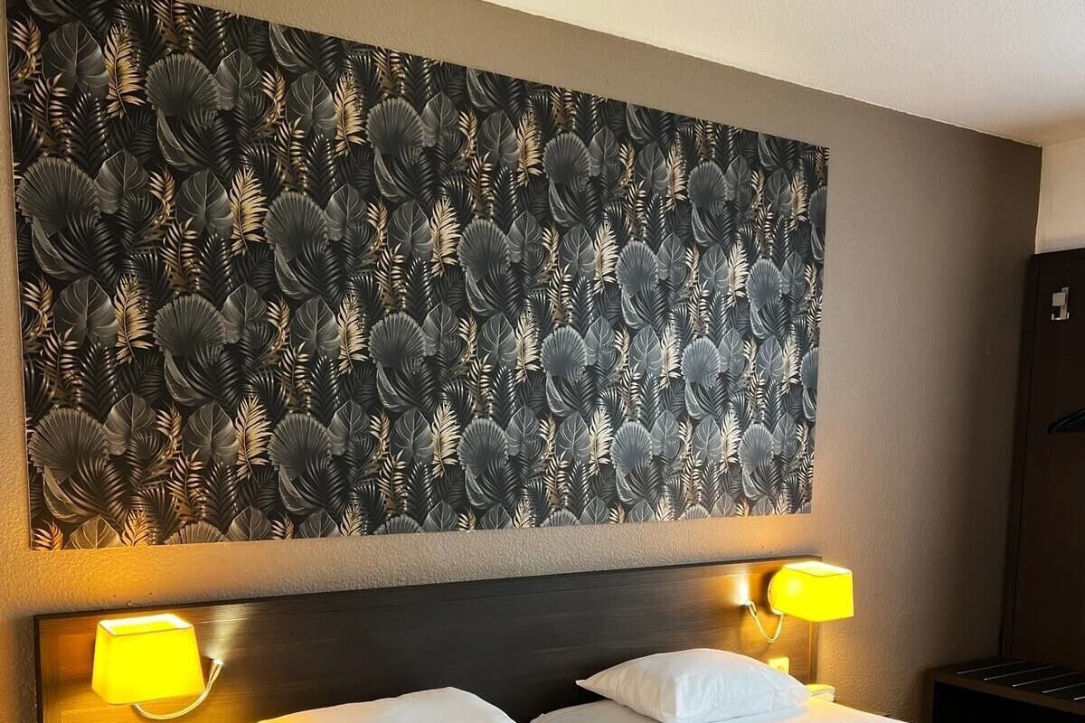 Une chambre d’hôtel avec deux lits, une grande fresque murale et deux lampes de chevet.
