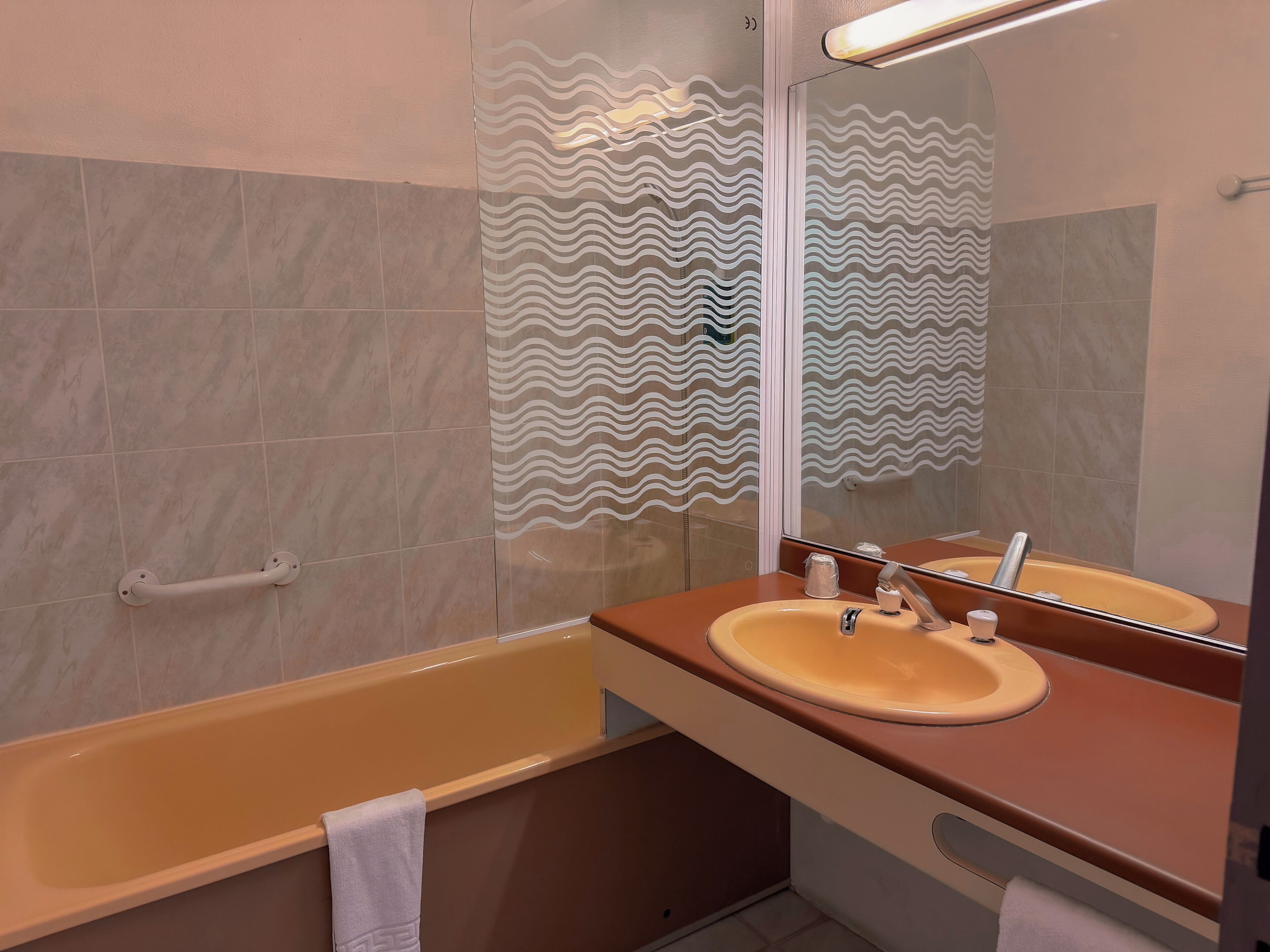 A modern bathroom with a bathtub, a vanity with a mirror, and a towel rack.